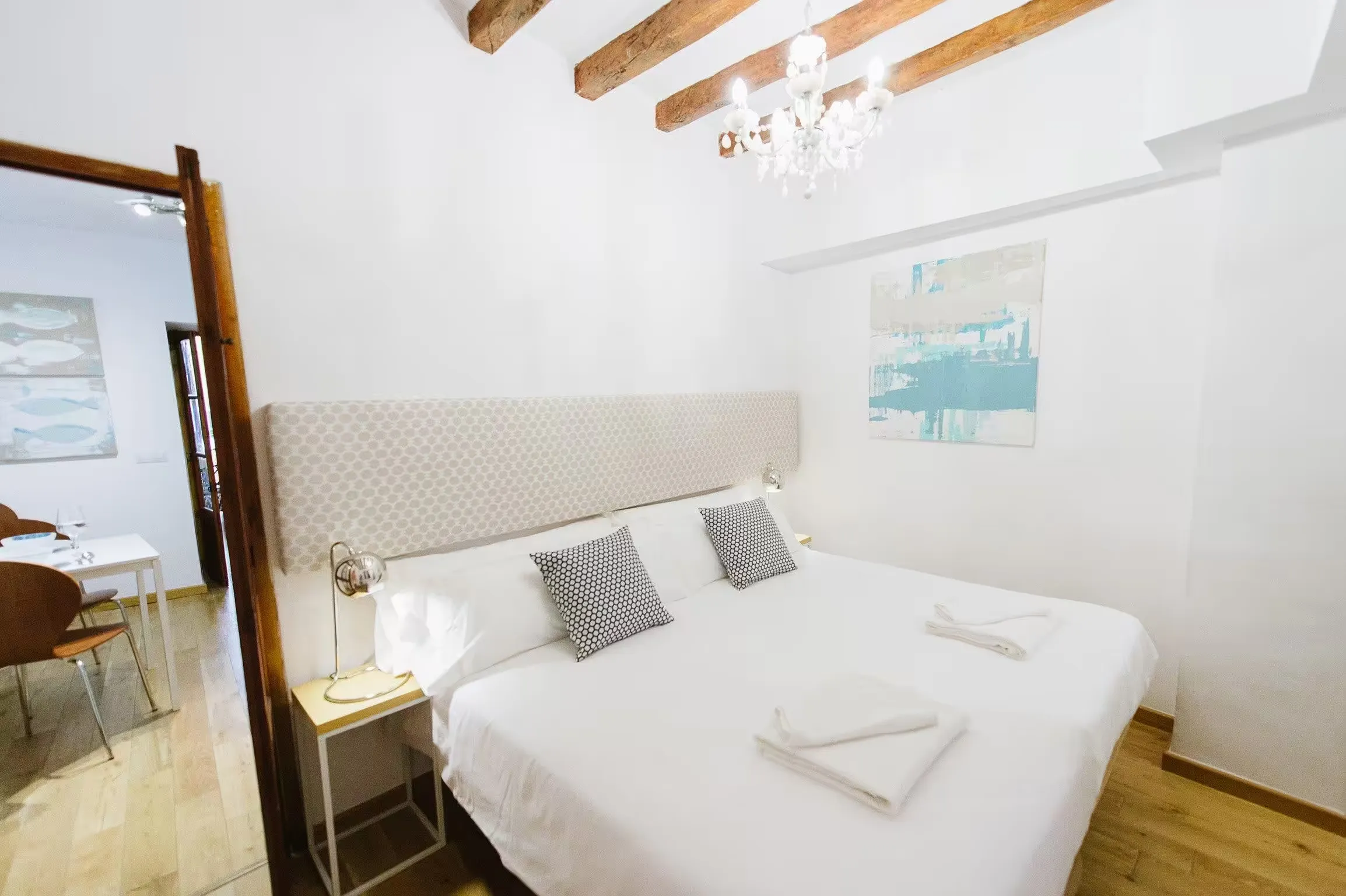 Bedroom at Casa Roca in Palma with exposed beams, a crystal chandelier and a padded headboard