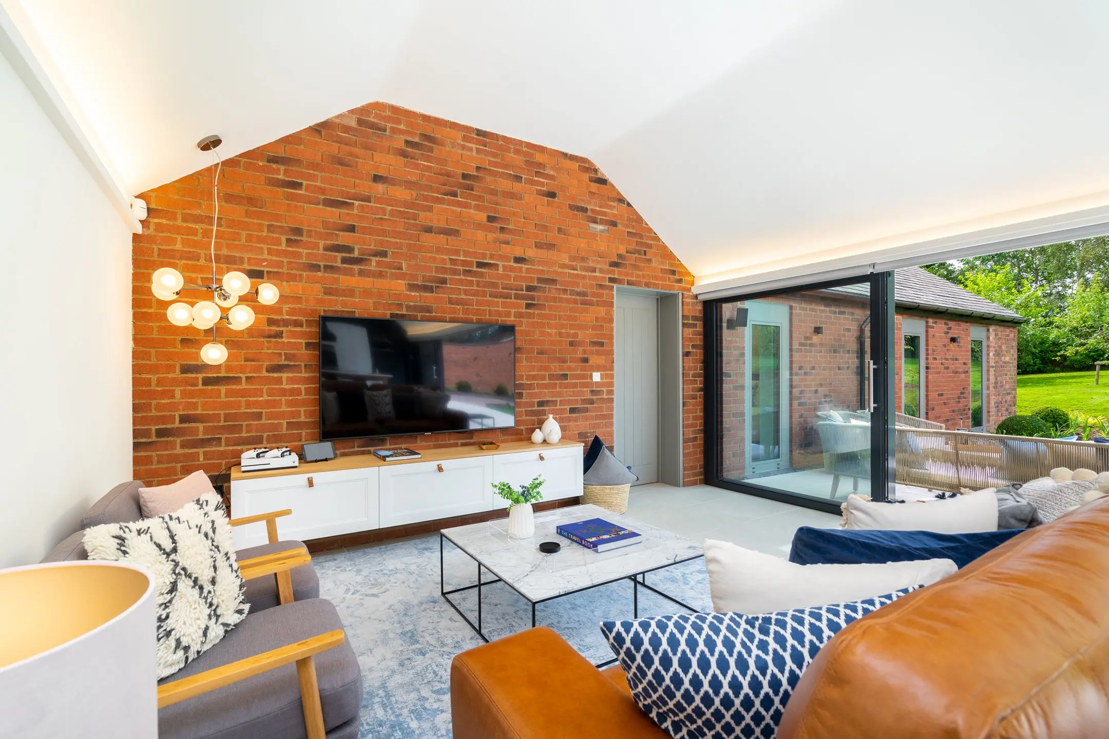 Converted brick interior at the Clipston estate with an exposed gable wall and sliding glass doors onto the garden