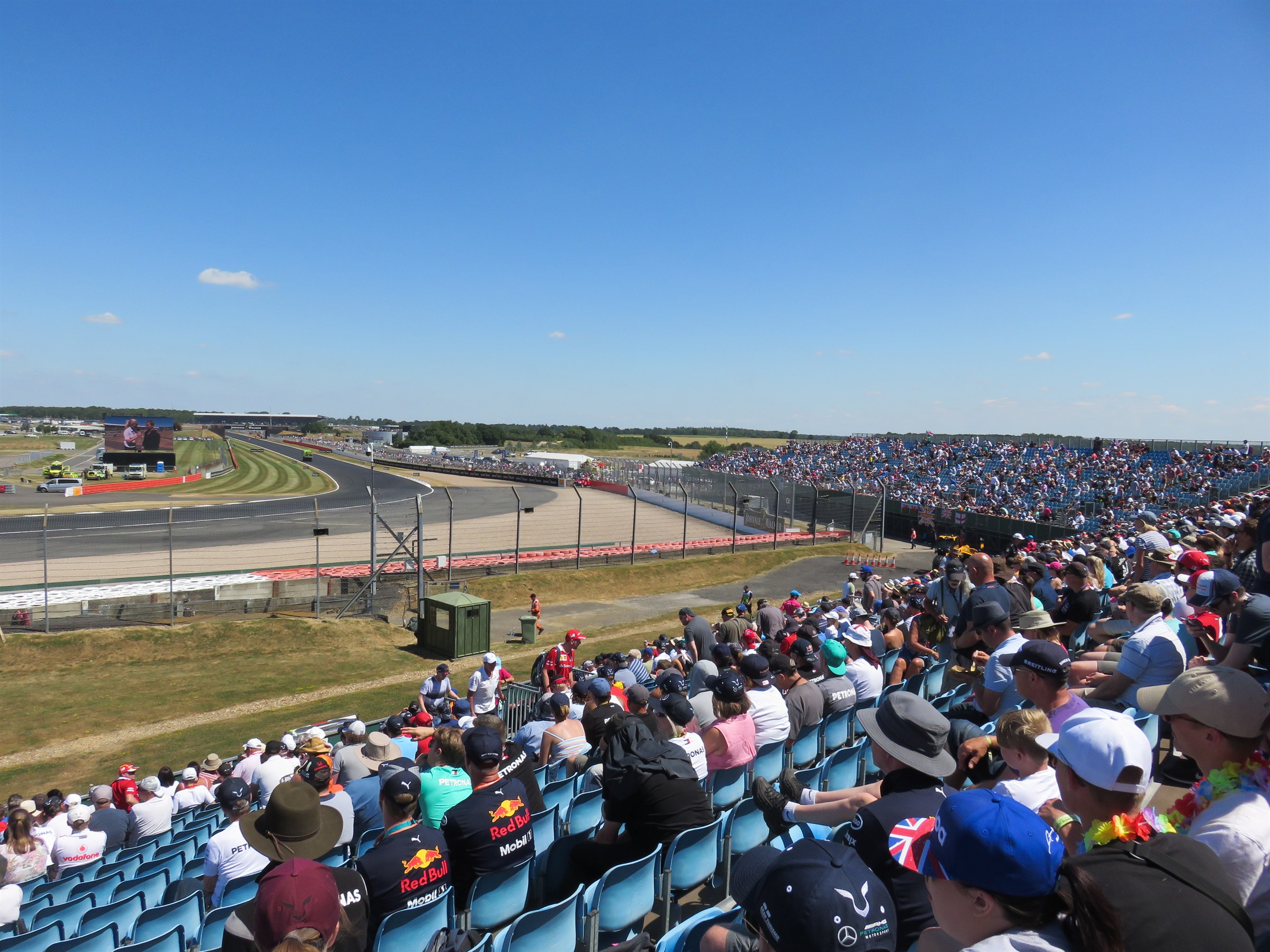 Packed grandstand of spectators watching cars on track at the British Grand Prix at Silverstone