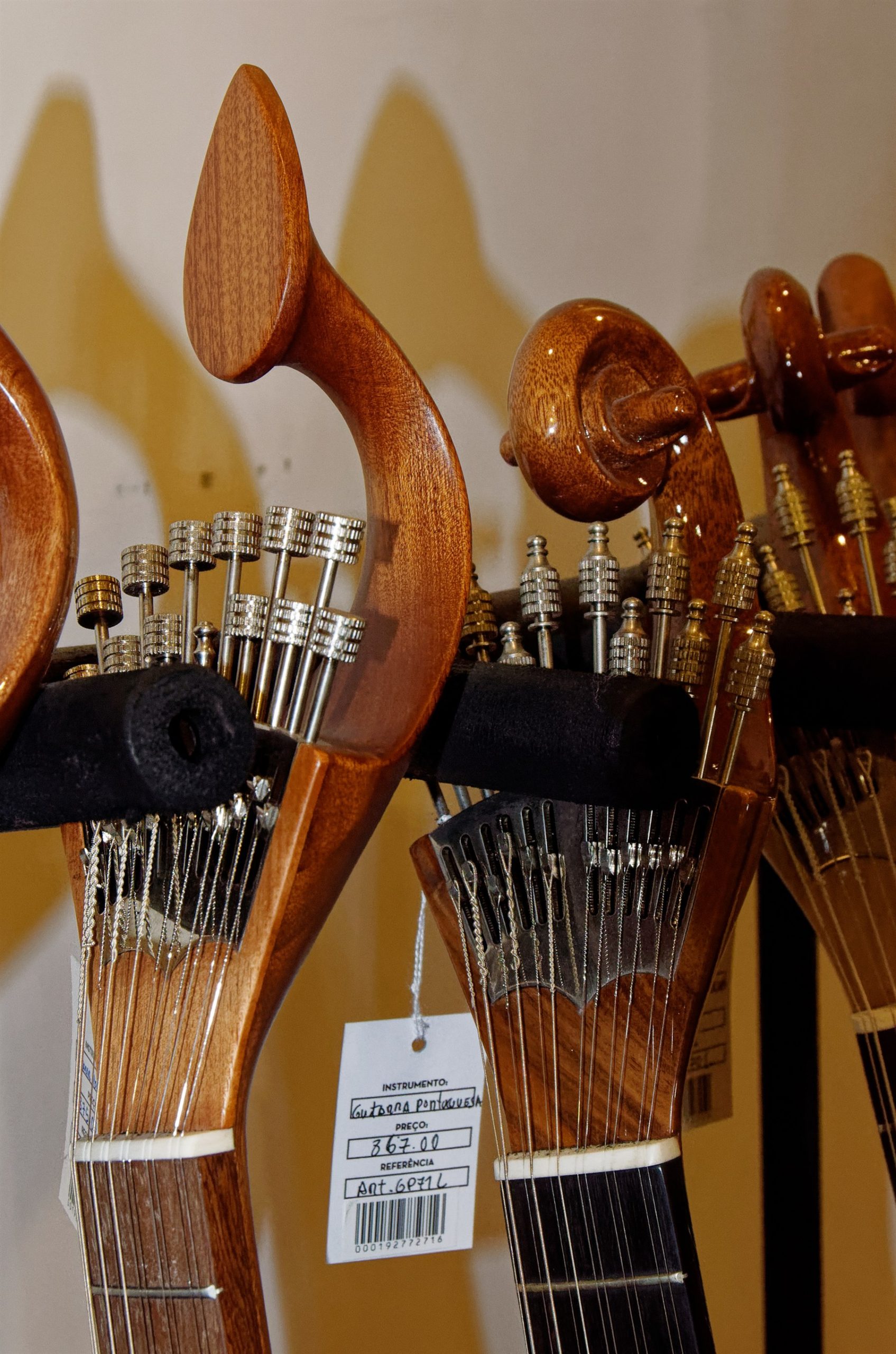 Row of guitarra portuguesa headstocks on a rack at Casa da Guitarra in Porto, one with a price tag