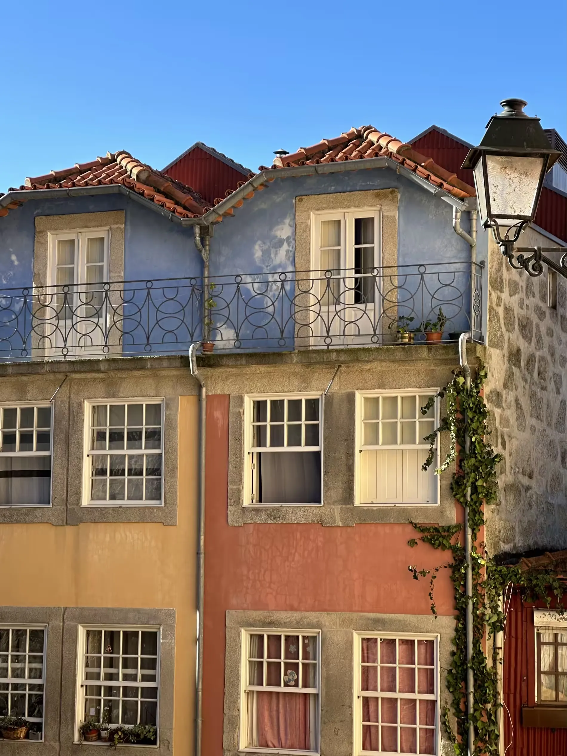 Pastel-painted townhouses with terracotta roofs and an ironwork balcony in the Ribeira district of Porto