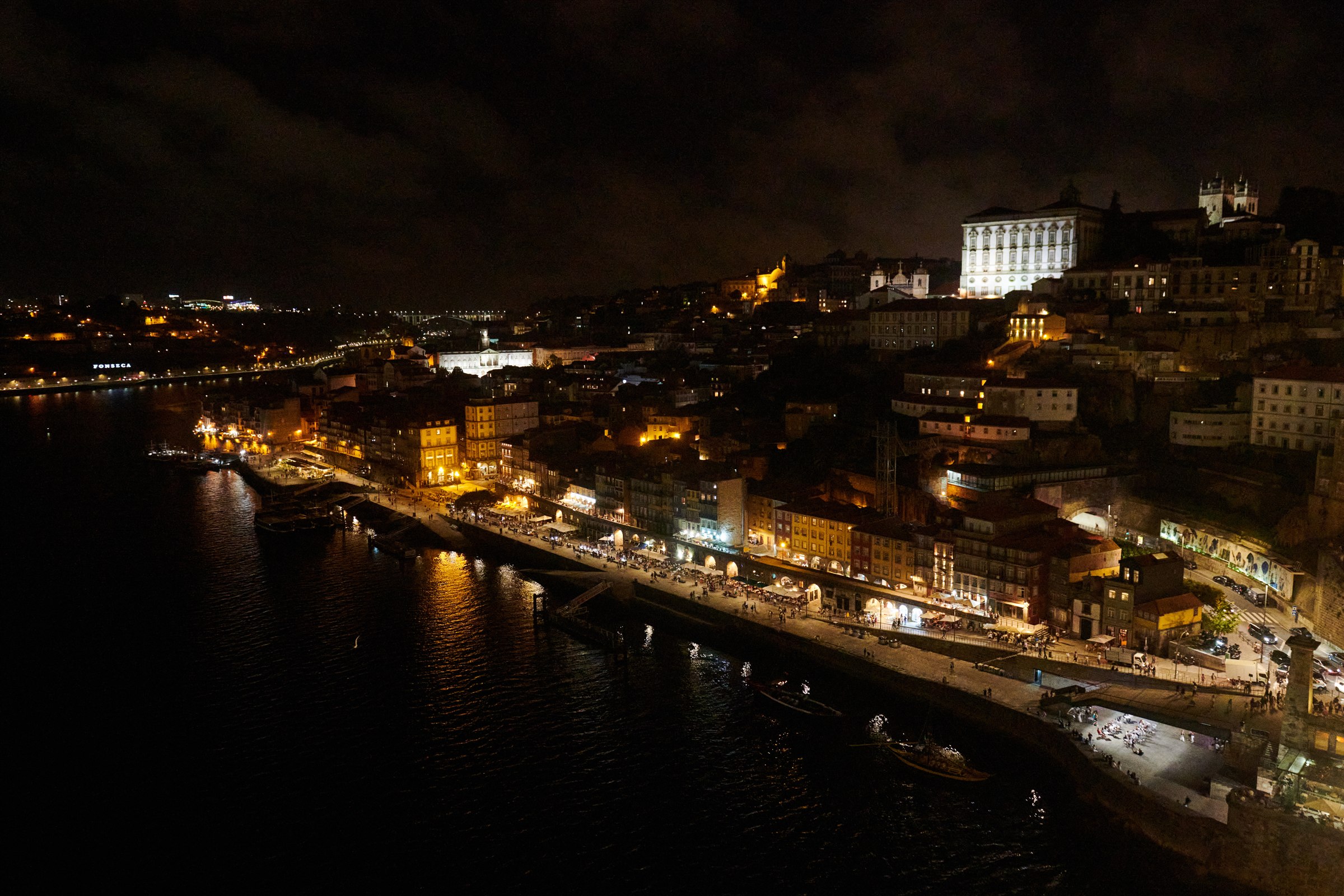 Porto Ribeira waterfront lit at night seen from the Dom Luis I bridge with rabelo boats on the Douro