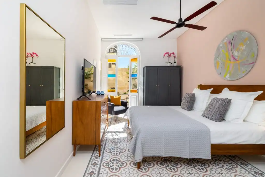 Master suite at Aster House in Sliema with a superking bed, patterned Maltese floor tiles and arched doors