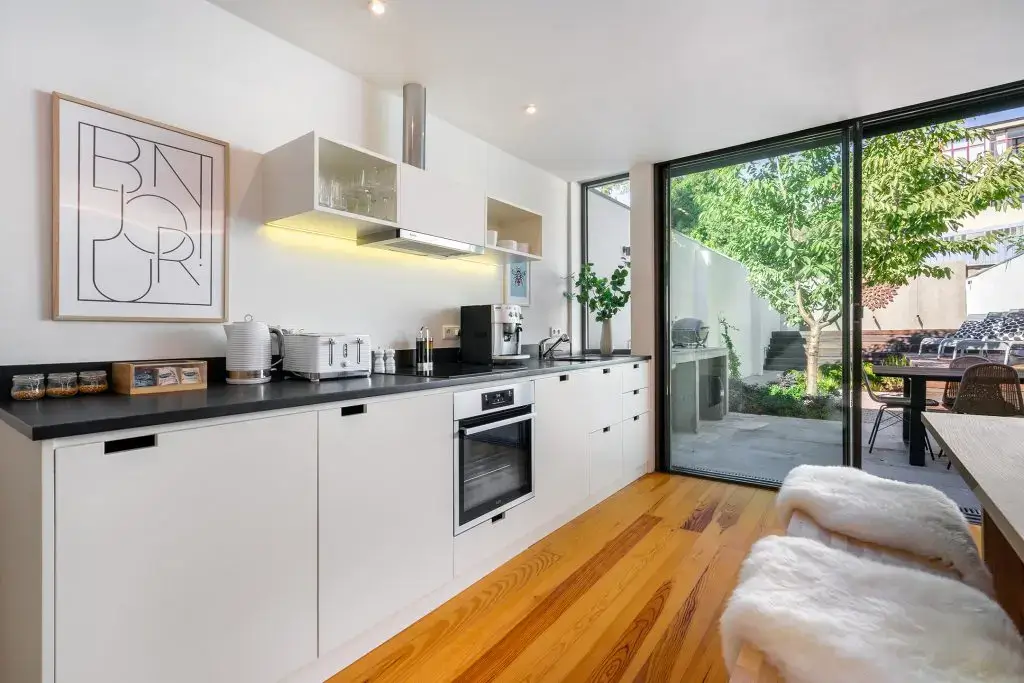 The kitchen at Villa Almada in Porto with a dark stone worktop, built-in oven and full-height glass doors onto the garden