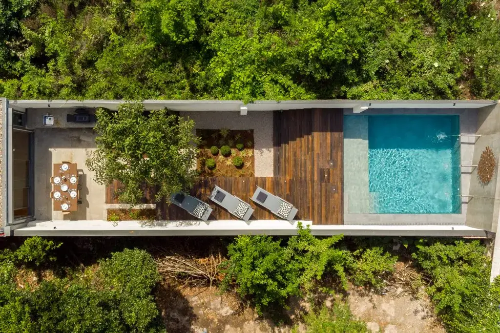 Overhead view of Villa Almada in Porto showing the dining terrace, planted garden, timber deck with loungers and the private pool