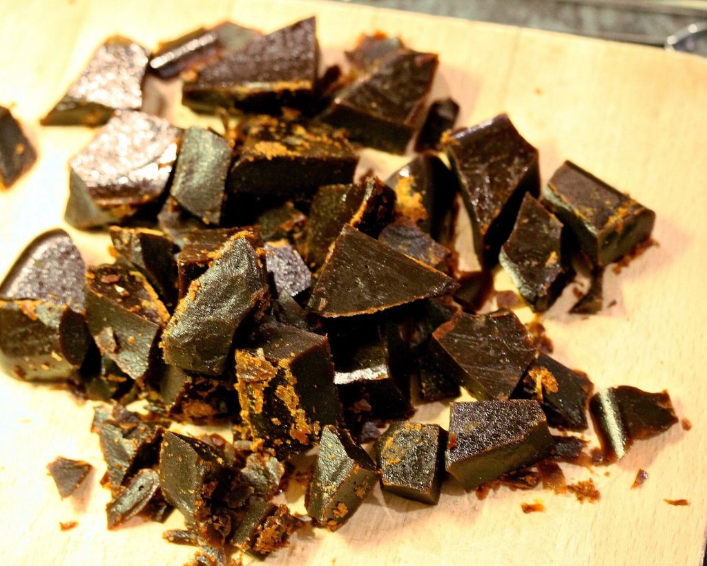 Home-made bonfire toffee broken into dark glossy pieces on a wooden board