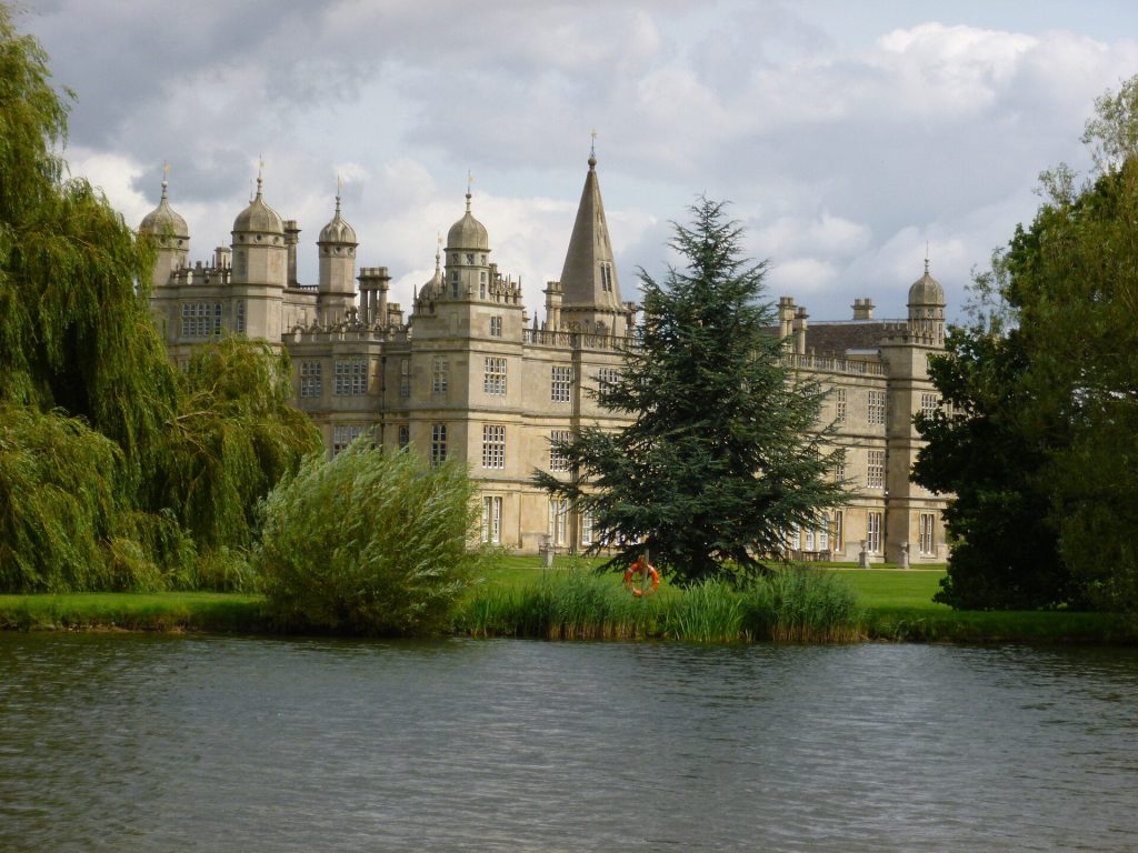 Burghley House near Stamford seen across the lake with willows and a cedar tree