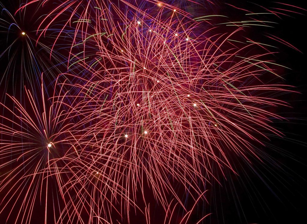 Red and purple fireworks bursting across the night sky over Ashby St Ledgers in Northamptonshire on Bonfire Night