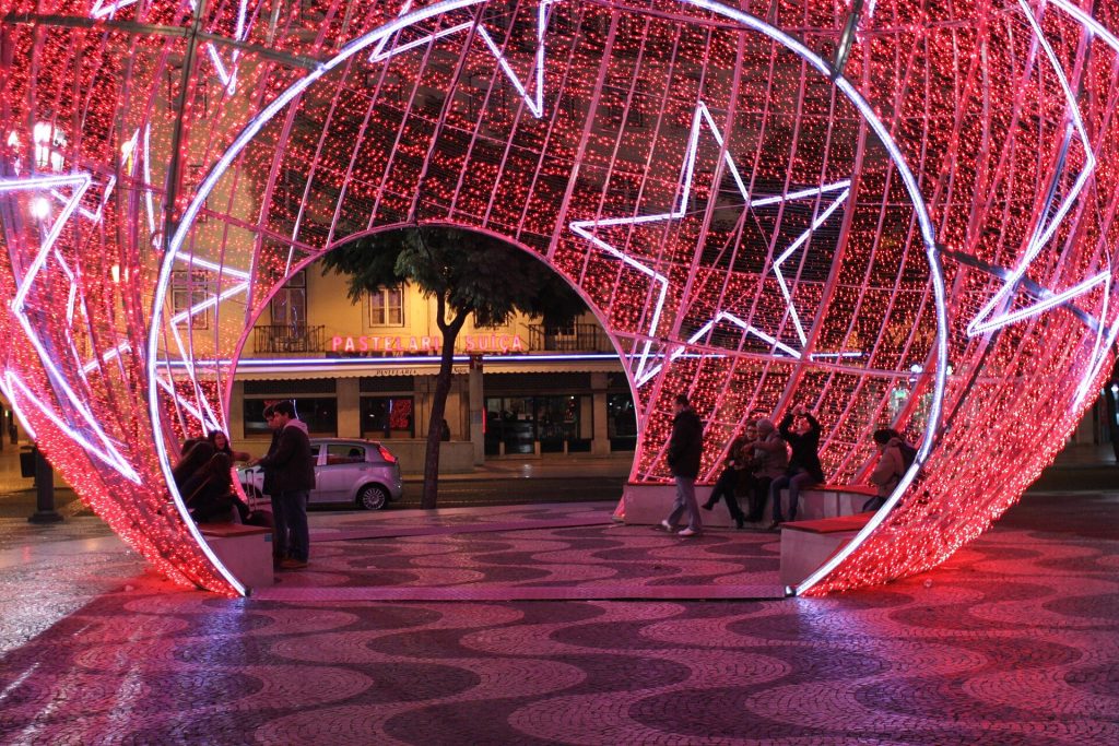 A giant illuminated Christmas bauble on the patterned paving of Rossio square in Lisbon at night