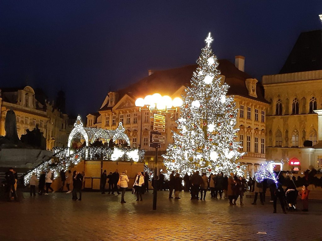 The tall lit Christmas tree and market stalls on Old Town Square in Prague at night