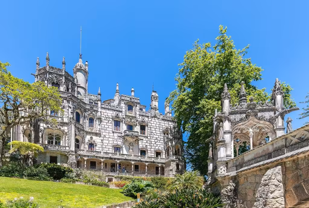 The carved stone facade and turret of the palace at Quinta da Regaleira in Sintra seen from the lawn