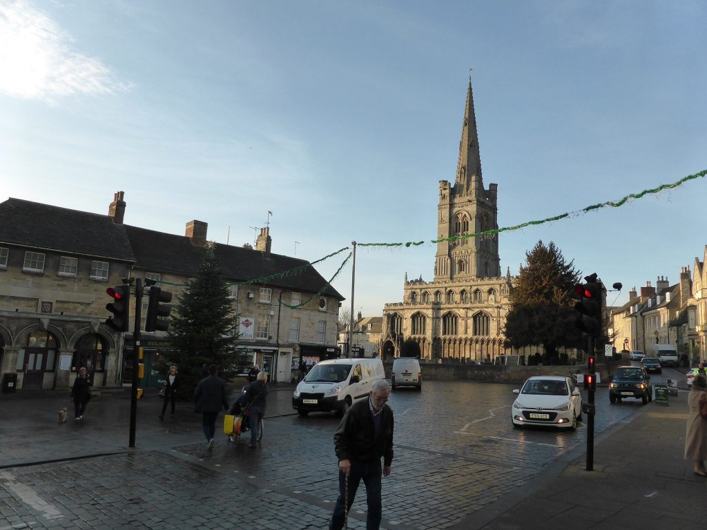 Red Lion Square in Stamford at Christmas with a decorated tree, festive garlands and All Saints Church spire